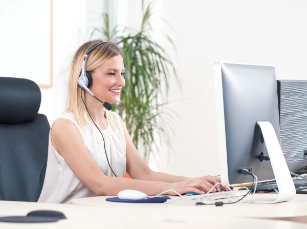 Portrait of smiling young woman working on a computer in a call center